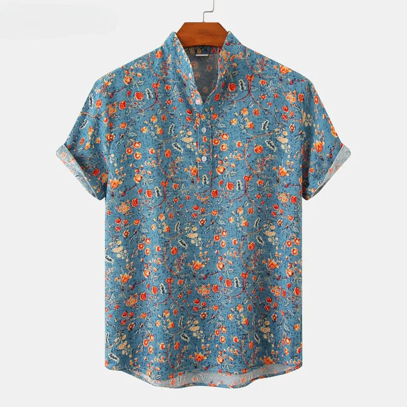 A short-sleeved, blue cotton shirt with a classic floral pattern in red, orange, and yellow, hanging on a wooden hanger against a plain white background.
