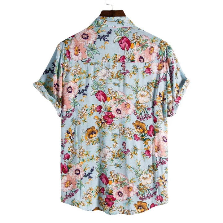 A short-sleeved, light blue luxury linen shirt with a colorful floral pattern in pink, yellow, purple, and white. Shown on a hanger from the back view, this Men's Genuine Linen Shirt offers breathable comfort and vibrant style.