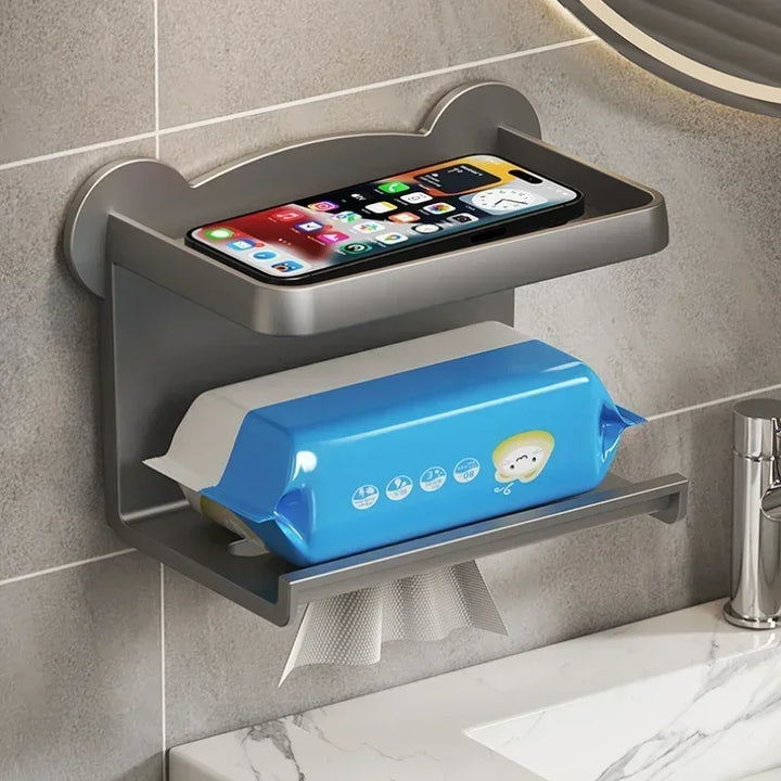 A wall-mounted, moisture-resistant gray shelf with two tiers: the top holds a smartphone, and the bottom holds a blue wet wipes container dispensing tissues, next to a bathroom sink—offering a smart, multi-functional shelf solution.