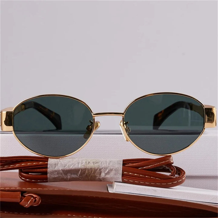 A pair of vintage-inspired sunglasses with gold metal frames and dark lenses is displayed against a white background, with a brown leather case and matching strap beneath them, blending timeless Italian style with UV400 protection.