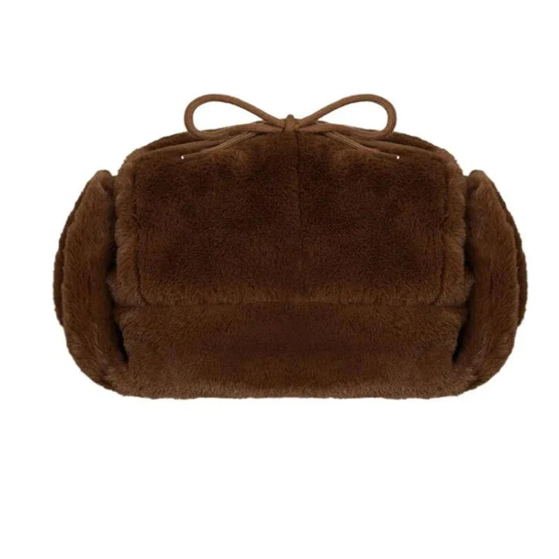 A brown, rectangular plush handbag featuring soft, furry material, rounded sides, and a bow detail on top—perfect for winter styling.