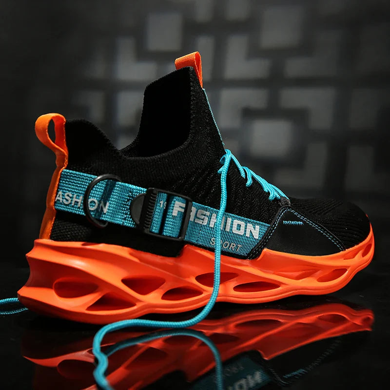 A stylish black Extreme VS7 Sneaker with a bright orange sole and accents, blue laces, and a blue strap labeled FASHION. This streetwear sneaker is displayed against a dark, blurred background.
