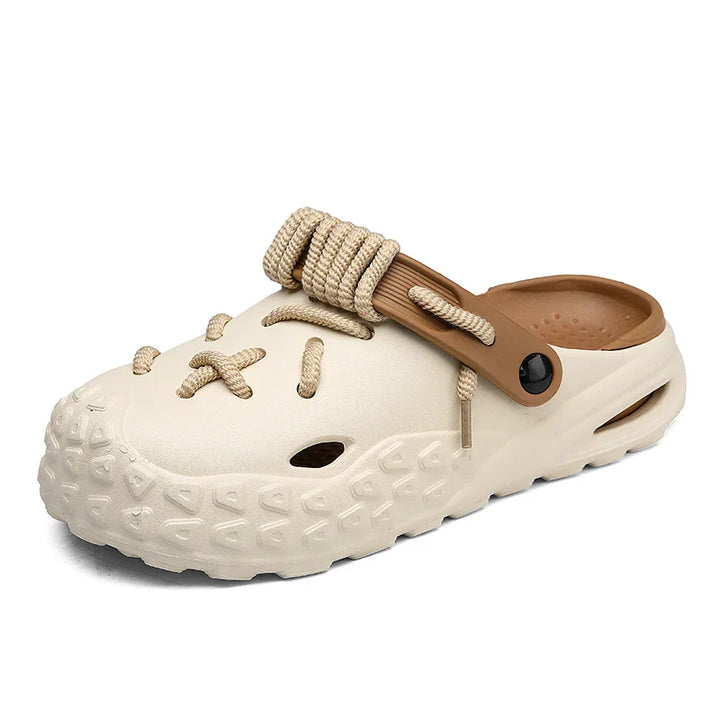 A beige slip-on clog with a textured sole for enhanced grip, decorative rope laces on top, and a brown adjustable heel strap. The shoe features unique rope details resembling hiking boot laces.