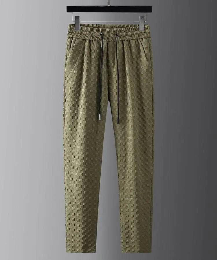 Olive green textured jogger pants with an elastic drawstring waistband, ultra-soft fabric, and side pockets, hanging on a black clothes hanger against a plain gray background.