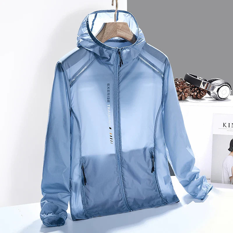 A light blue, hooded, zip-up windbreaker jacket hangs on a wooden hanger. Made from quick-dry material, the jacket has black zipper pockets and “Exercise Training” text on the front. A desk with headphones and books is in the background.