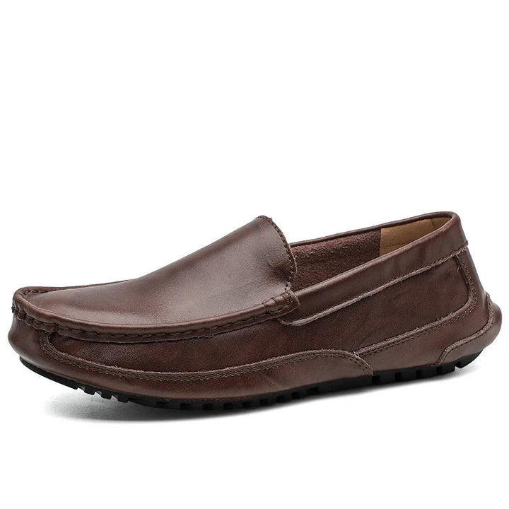 A brown hand-stitched moccasin loafer with visible stitching, a round toe, and a textured black rubber sole, featuring a cushioned insole for comfort. Photographed against a white background.