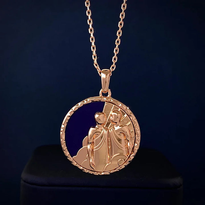 A gold pendant necklace featuring an intricate design of two abstract figures within a circular frame, this zodiac necklace is elegantly displayed against a dark background.