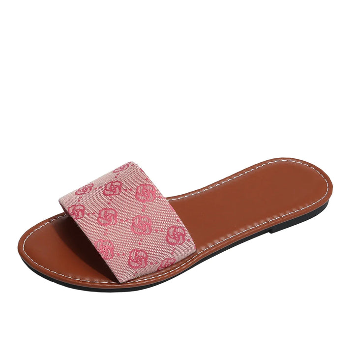 A brown flat sandal in a slide silhouette with white stitching, featuring a wide pink strap decorated with a repeating double-G logo pattern—a timeless shoe from French Sole.
