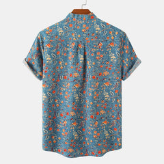 A classic design, this short-sleeve button-up cotton shirt showcases a blue background with a colorful floral pattern in red, orange, yellow, and white, displayed on a hanger against a plain background.