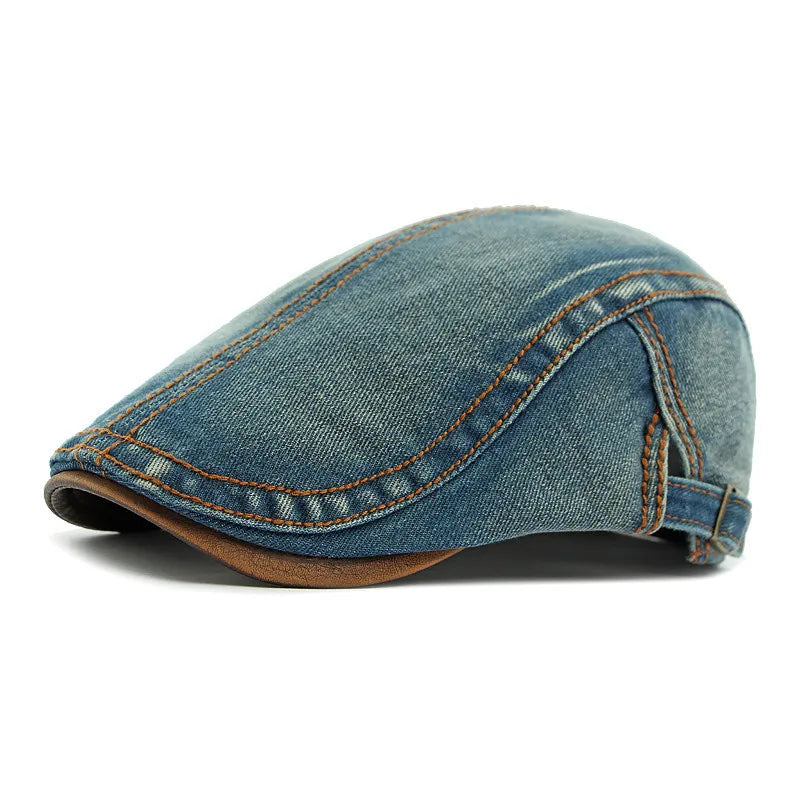 A blue denim flat cap with brown stitching, displayed in a side view against a white background, offers unisex style and sun protection.