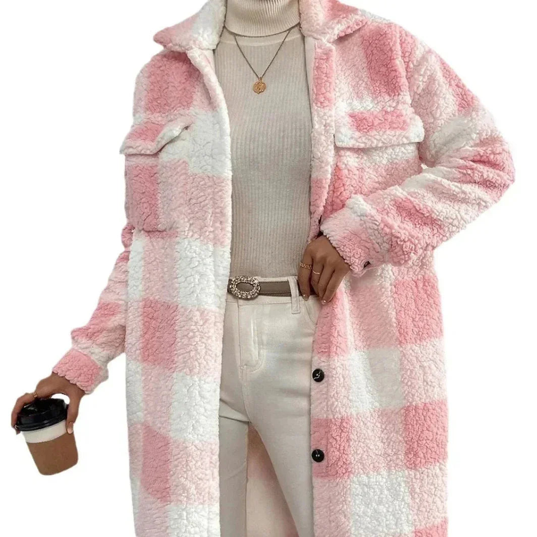 A person wearing a pink and white plaid Sherpa fluffy coat with an open lapel over a beige turtleneck sweater, white pants, and a belt, holding a takeaway coffee cup in one hand.