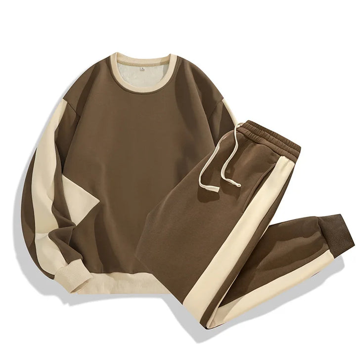 A brown and beige color-blocked sweatshirt and matching jogger pants set in a soft cotton blend, displayed on a white background. Cream accents and a drawstring waist enhance this relaxed fit, perfect for casual loungewear.