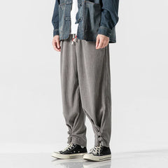 A person wears gray, loose-fitting cotton blend sweatpants with an adjustable fit and drawstring ties at the ankles, black Converse sneakers, a white shirt, and a denim jacket. Only the lower half of the body is visible.