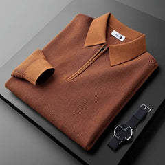 A neatly folded brown zip-collar sweater made from stretchy fabric is displayed on a dark surface next to a black wristwatch with silver details. The sweater’s sleeve is folded once, and a tag is visible inside the collar.