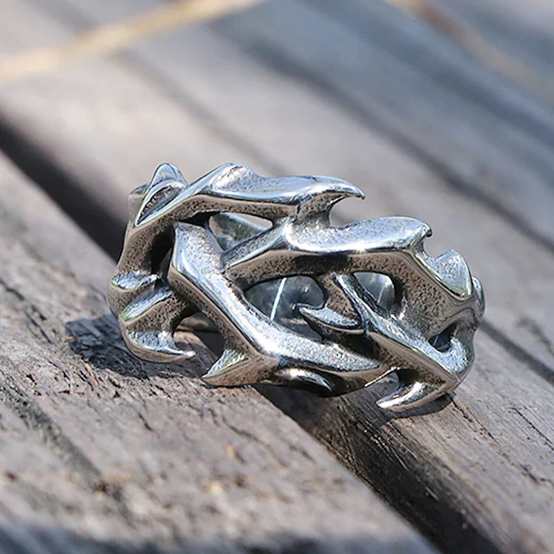 A silver streetwear ring designed to resemble intertwined thorny branches, resting on weathered wooden planks, perfect for those who appreciate bold fashion jewelry.