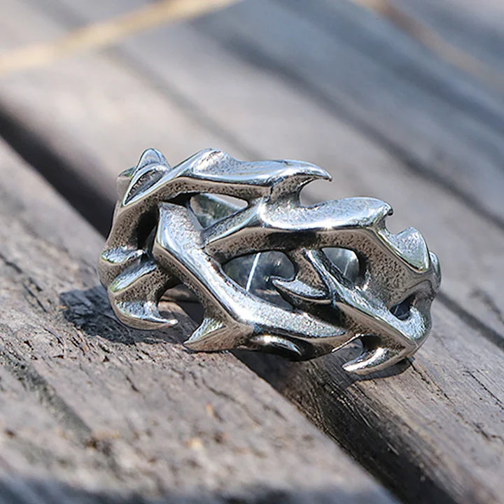 A silver streetwear ring designed to resemble intertwined thorny branches, resting on weathered wooden planks, perfect for those who appreciate bold fashion jewelry.
