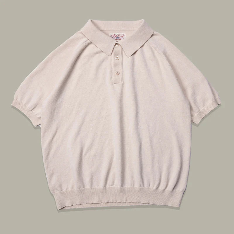 A beige mens polo shirt in classic style, crafted from soft organic cotton knit, features a collar, three buttons at the neck, and ribbed cuffs and hem, laid flat on a light gray background.