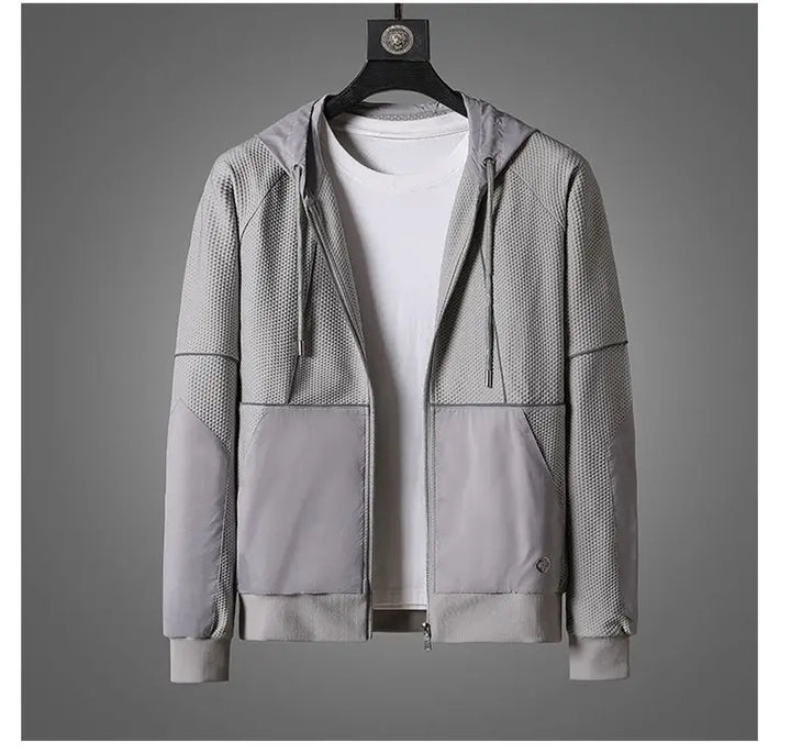 A light gray zipper hoodie with mesh-textured panels and moisture wicking fabric is displayed on a hanger over a plain white T-shirt, set against a neutral gray background.