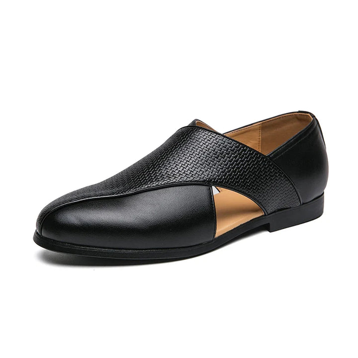 A stylish black formal shoe with a textured upper, smooth leather sections, and a unique side cutout design. These genuine leather loafers feature a low heel, tan inner lining, and a durable outsole for lasting comfort.