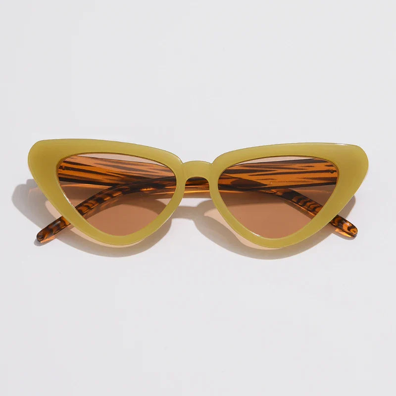Cat-eye sunglasses with thick yellowish-green frames and brown-tinted lenses, offering UV400 sun protection. The temples feature a subtle striped pattern, adding flair to this lightweight eyewear, displayed on a white background.