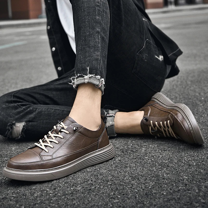 A person wearing ripped black jeans and brown casual sneakers with RunForm insoles sits on an asphalt street, legs crossed. The focus is on stylish shoes featuring distressed denim and enhanced comfort.