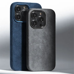 Two smartphones with triple camera setups stand upright, each wrapped in minimalistic Alcantara phone cases. The dark blue and black cases feature a smooth, suede finish that offers both a premium feel and protective design.