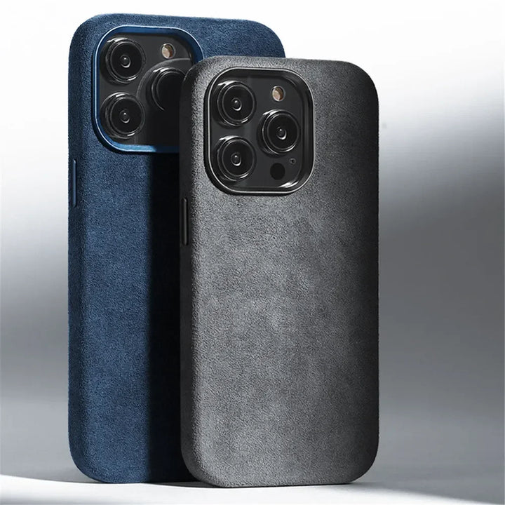 Two smartphones with triple camera setups stand upright, each wrapped in minimalistic Alcantara phone cases. The dark blue and black cases feature a smooth, suede finish that offers both a premium feel and protective design.