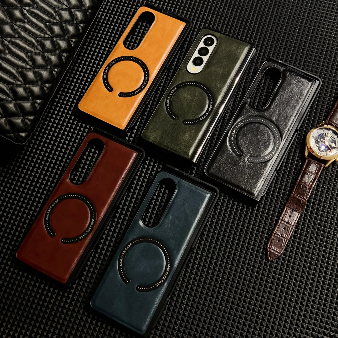 Five leather cases, including a Samsung Galaxy Z Fold case, in brown, green, black, burgundy, and blue are displayed on a textured black surface beside a brown leather wristwatch and a partially visible quilted black object.