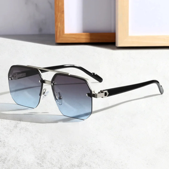 A pair of stylish sunglasses with large, geometric blue gradient UV400 protective lenses and black arms, resting on a light-colored surface with a wooden picture frame in the background.