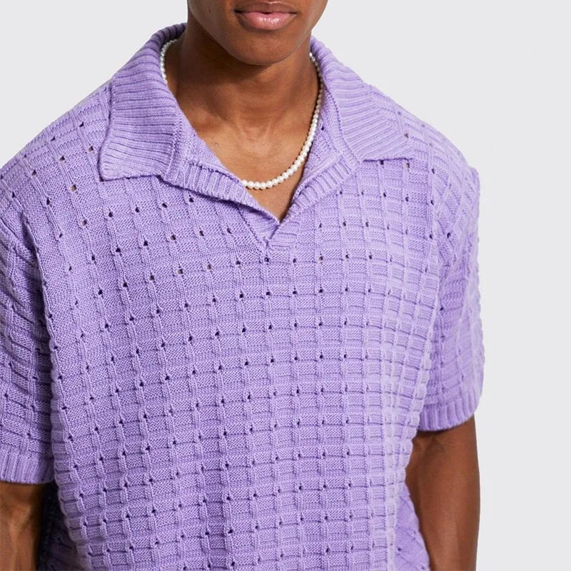 A person wearing a light purple, short-sleeve, breathable knit design shirt with a collar and a pearl necklace, shown from the shoulders to the waist against a plain background.