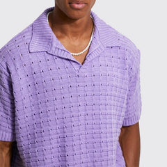 A person wearing a light purple, short-sleeve, breathable knit design shirt with a collar and a pearl necklace, shown from the shoulders to the waist against a plain background.