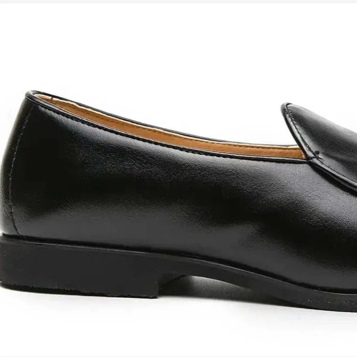A black leather slip-on dress shoe with a low heel and cushioned insole, shown from the side against a white background.