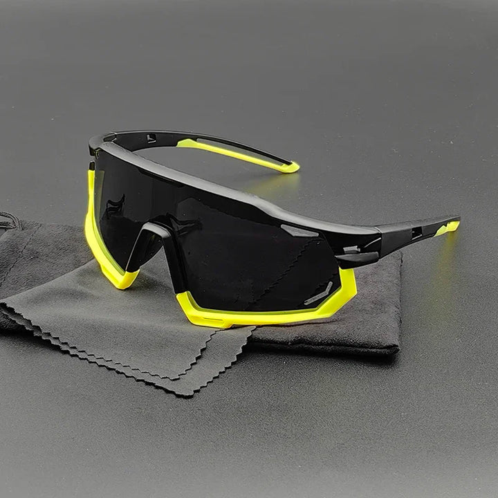 Sporty black Olympus Sunglasses with yellow accents rest on a gray cleaning cloth and black pouch, displayed on a dark surface. The large, mirrored lenses offer UV protection in a modern, angular design.