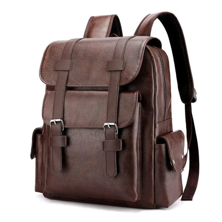 A brown leather backpack with spacious compartments, a large front flap, buckle straps, side pockets, and adjustable shoulder straps, standing upright on a white background.