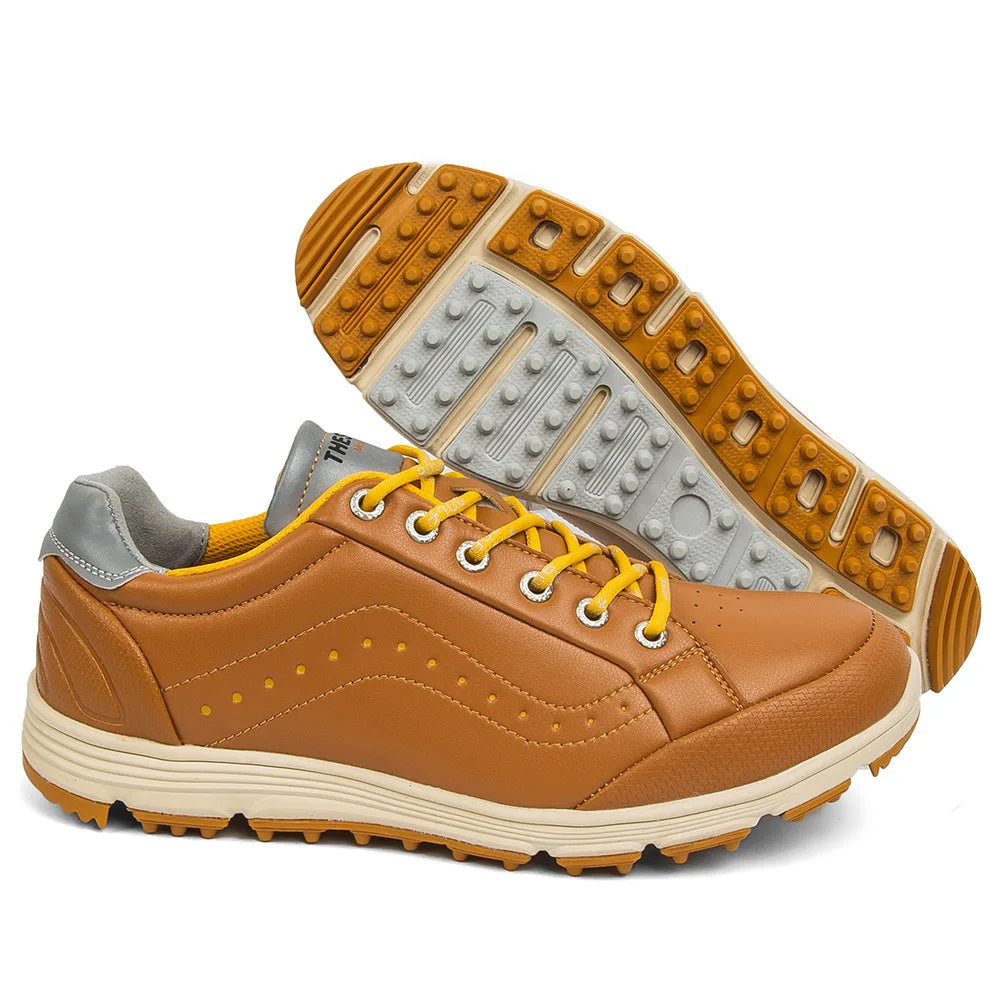 A pair of tan and yellow golf footwear with yellow laces, gray accents on the heel, and a textured rubber sole. One shoe is upright, while the other is displayed showing advanced cleat technology on the treaded sole.