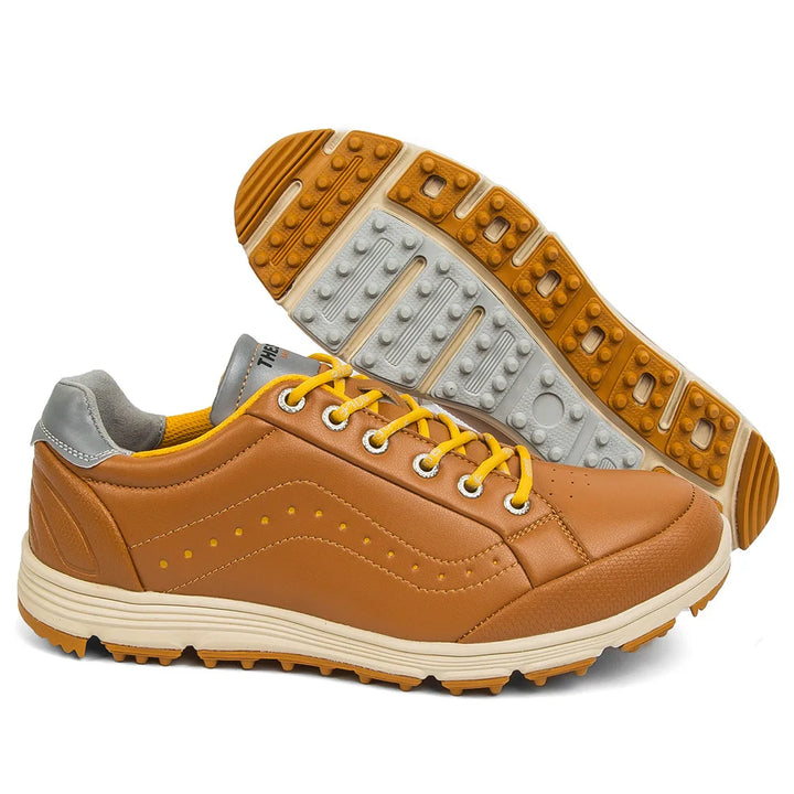 A pair of tan and yellow golf footwear with yellow laces, gray accents on the heel, and a textured rubber sole. One shoe is upright, while the other is displayed showing advanced cleat technology on the treaded sole.