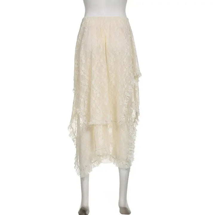 A cream-colored, high-waisted lace skirt with an asymmetrical hemline is displayed on a mannequin. The skirt features delicate floral lace detailing and layered, uneven edges for a romantic look.