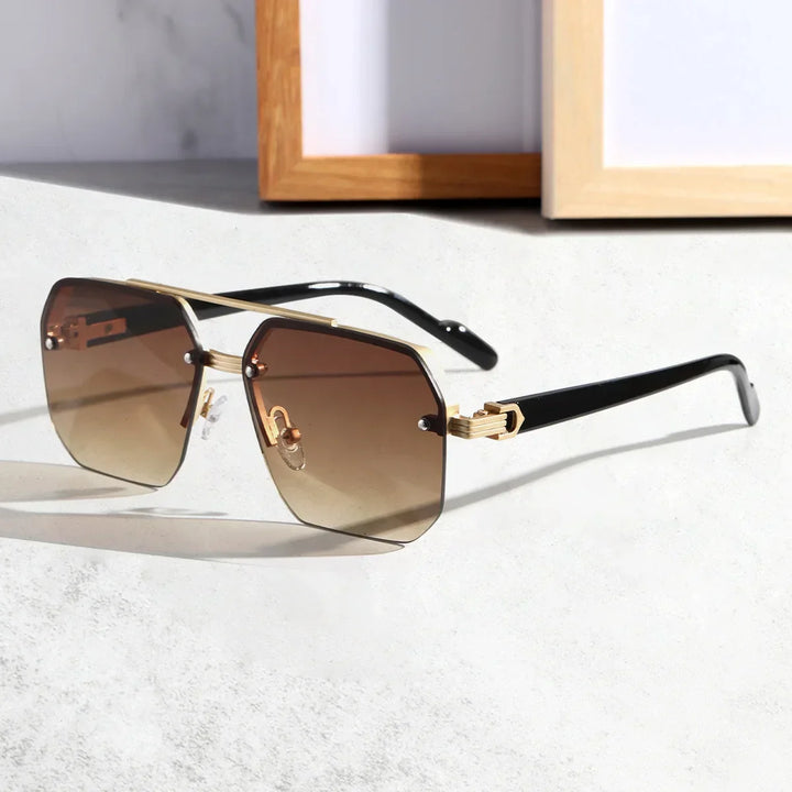 A pair of stylish sunglasses with a geometric metal frame, black arms, and large square brown gradient lenses featuring UV400 protective lenses, resting on a light-colored surface near a wooden picture frame.