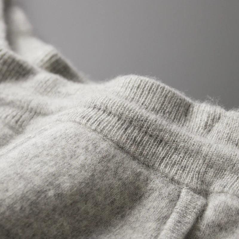 Close-up of light gray, soft fleece sweatpants with a tailored pencil cut, showing the elastic waistband and pocket seam, highlighting the cozy, winter warm fabric.
