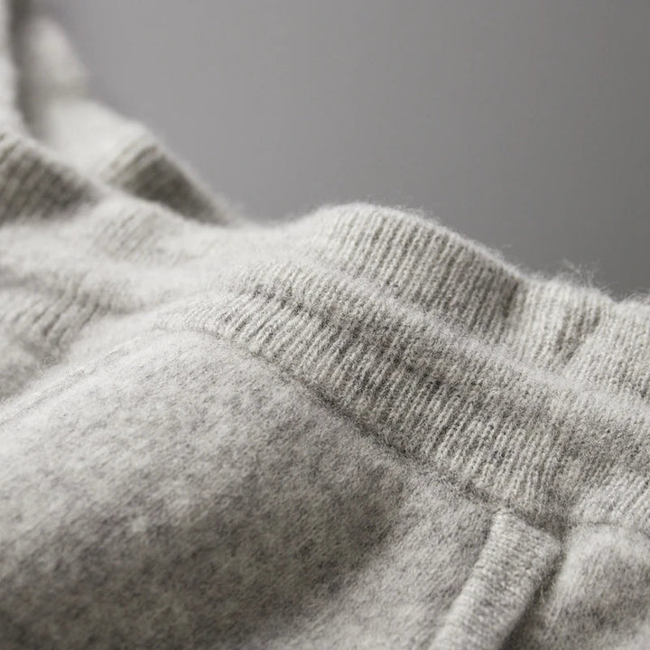 Close-up of light gray, soft fleece sweatpants with a tailored pencil cut, showing the elastic waistband and pocket seam, highlighting the cozy, winter warm fabric.