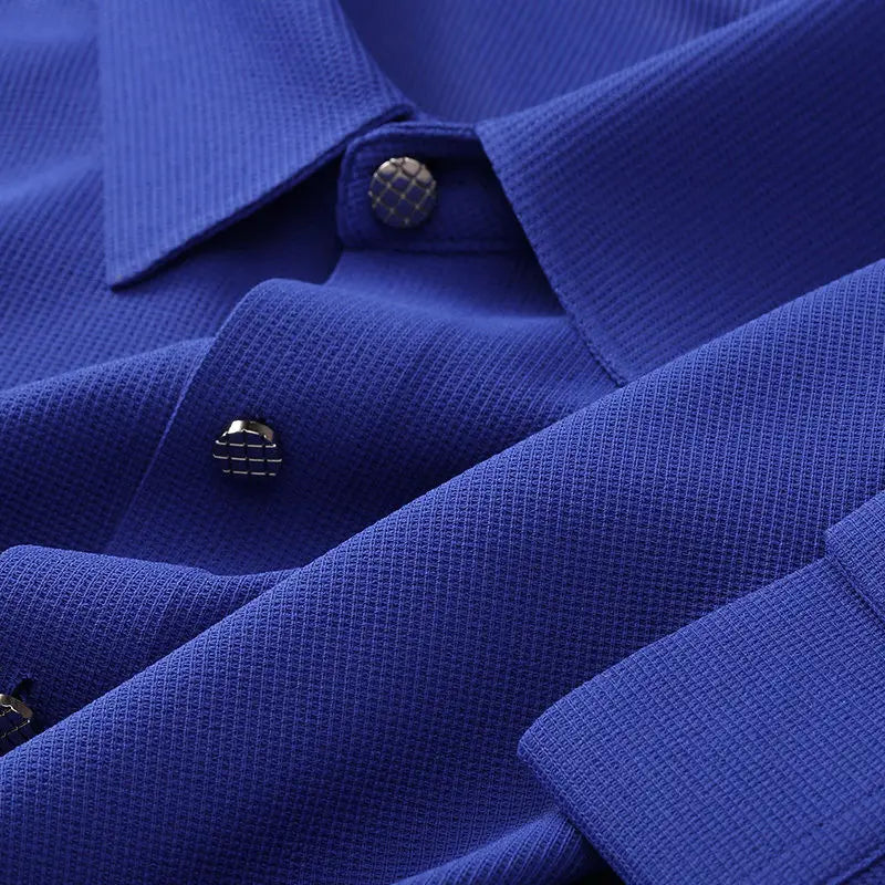 Close-up of a blue wrinkle-resistant shirt showing the collar, metallic grid-patterned buttons, and fabric texture. The shirt appears neatly pressed and stylish.