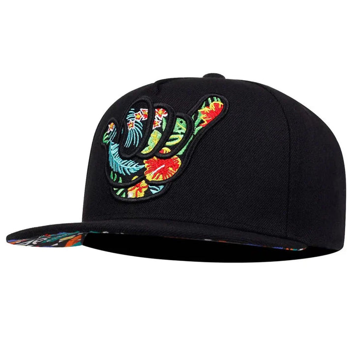A Hawaiian-inspired cap, this black Hang Loose Snapback features a raised embroidered shaka hand filled with colorful tropical floral patterns and the same vibrant design on the underside of the brim.