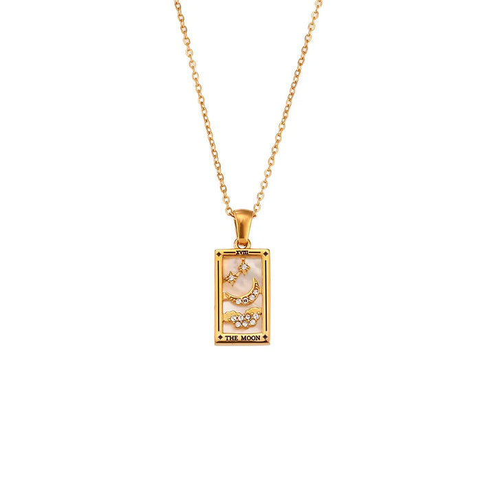 The Solaris Pendant Necklace is an 18K gold-plated chain featuring a rectangular pendant with a crescent moon, stars, blue enamel accents, and crystal details. The bottom of the pendant is inscribed with THE MOON.