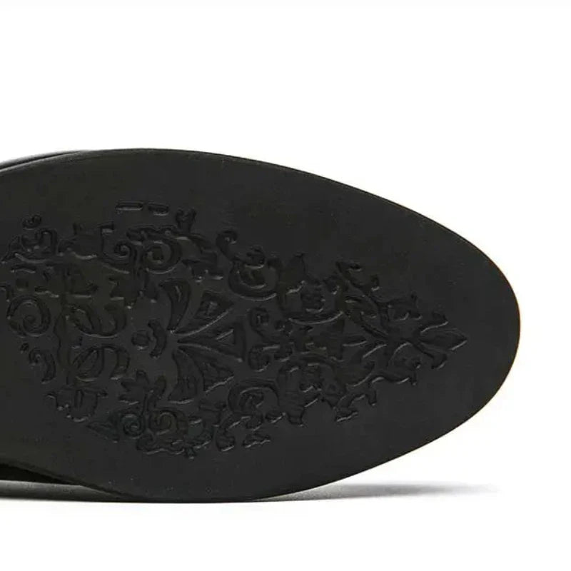 The image shows the black leather sole of a pointed shoe with an ornate, decorative swirl pattern etched into the bottom, giving it a subtle vintage look.