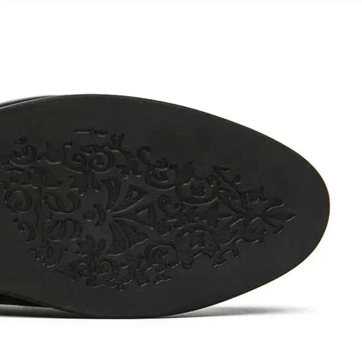 The image shows the black leather sole of a pointed shoe with an ornate, decorative swirl pattern etched into the bottom, giving it a subtle vintage look.