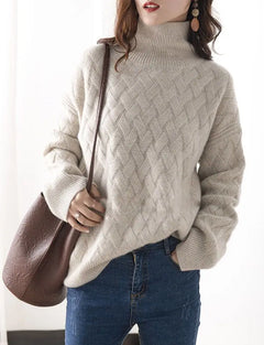 A woman wearing a cream-colored, ultra soft turtleneck sweater with a textured knit pattern and blue jeans, holding a brown shoulder bag. She has long, wavy hair and large dangling earrings. The background is softly lit.