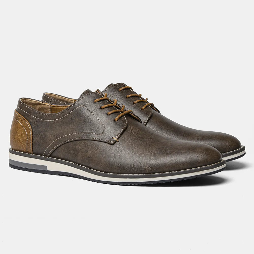 A pair of brown patchwork oxfords with tan detailing on the laces and heel, featuring white and black-striped rubber soles and a cushioned sole for extra comfort, displayed on a light gray background.