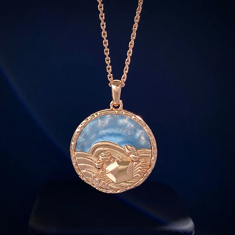 A gold pendant necklace featuring a round charm with a raised sailing boat on wavy water against a blue sky background, set on a simple gold chain with subtle astrology jewelry inspiration.