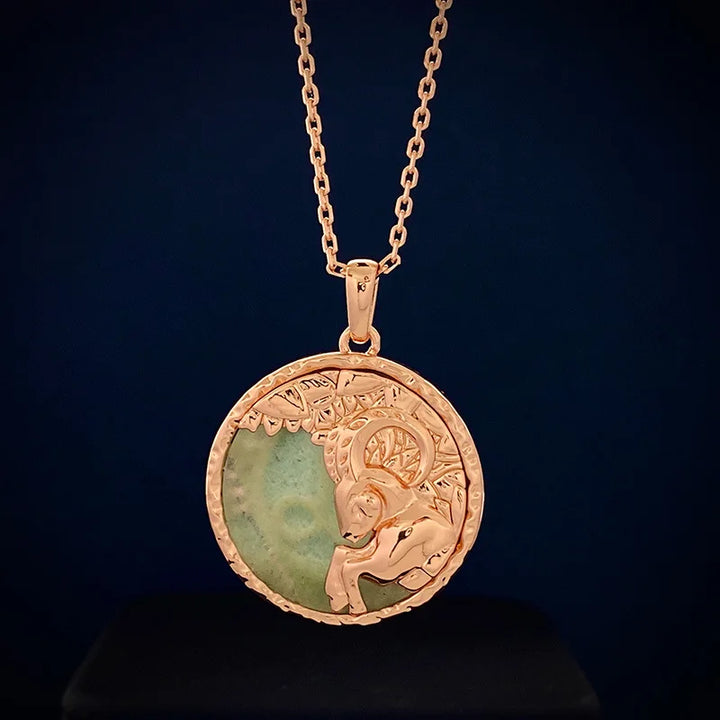 A gold zodiac necklace featuring an intricate ram design over a green circular stone, perfect for astrology jewelry lovers, displayed against a dark blue background.
