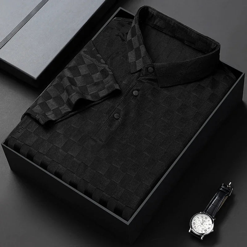 A neatly folded black checkered polo shirt with a tailored fit rests in a box, placed on a black surface next to a black wristwatch with a silver face.